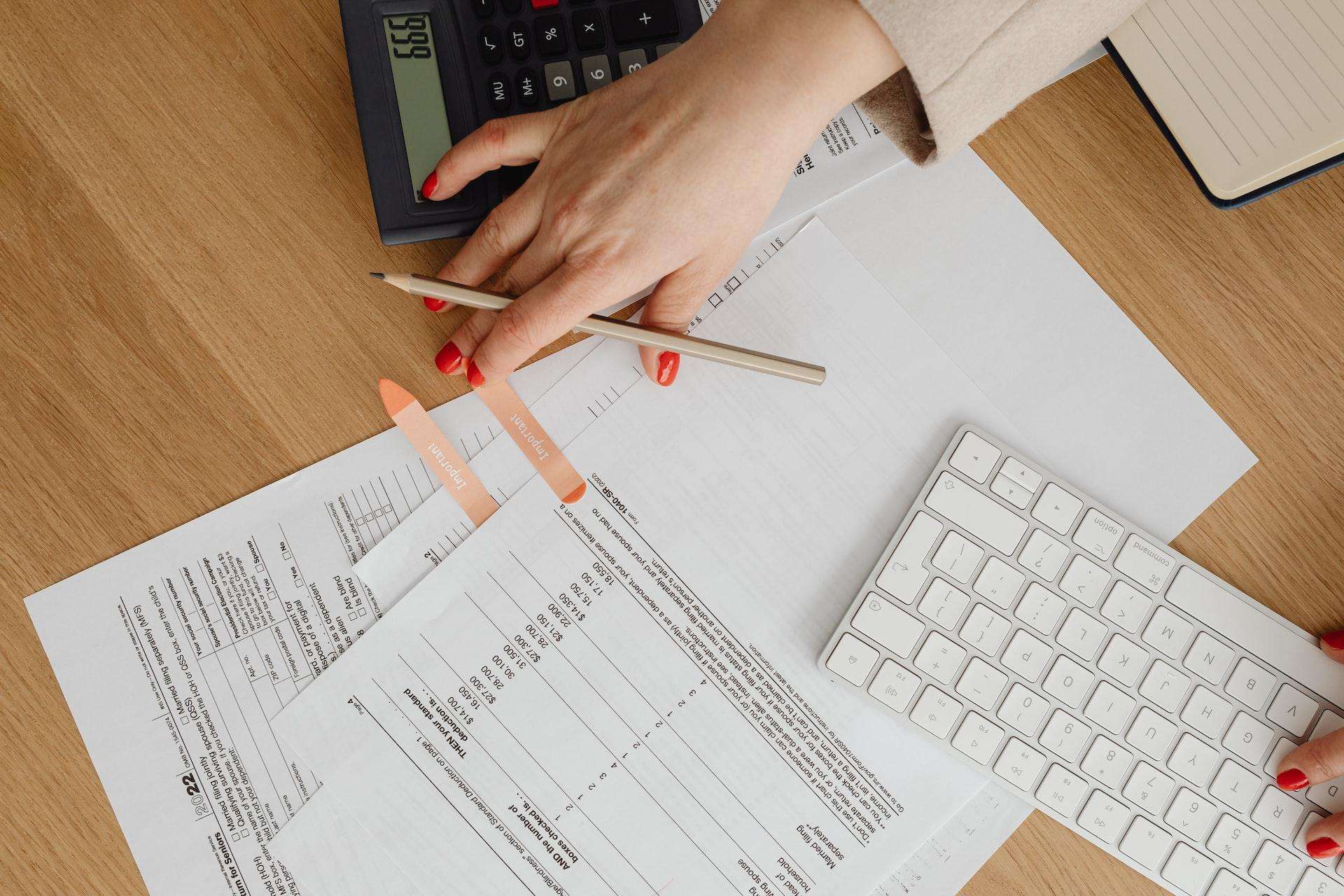 Business owner managing the annual filing requirements of a Singapore company with documents, pencil, calculator, and keyboard on a table