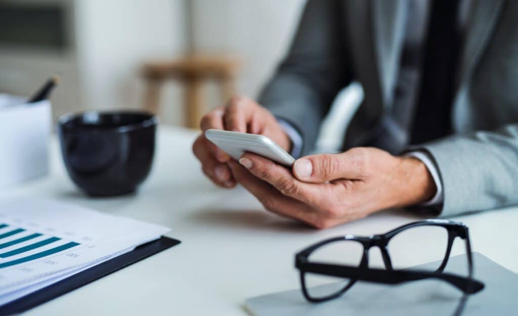 Business owner checking his phone to see the amount of profit his company has made without being taxed with Capital Gains Tax (CGT) in Singapore