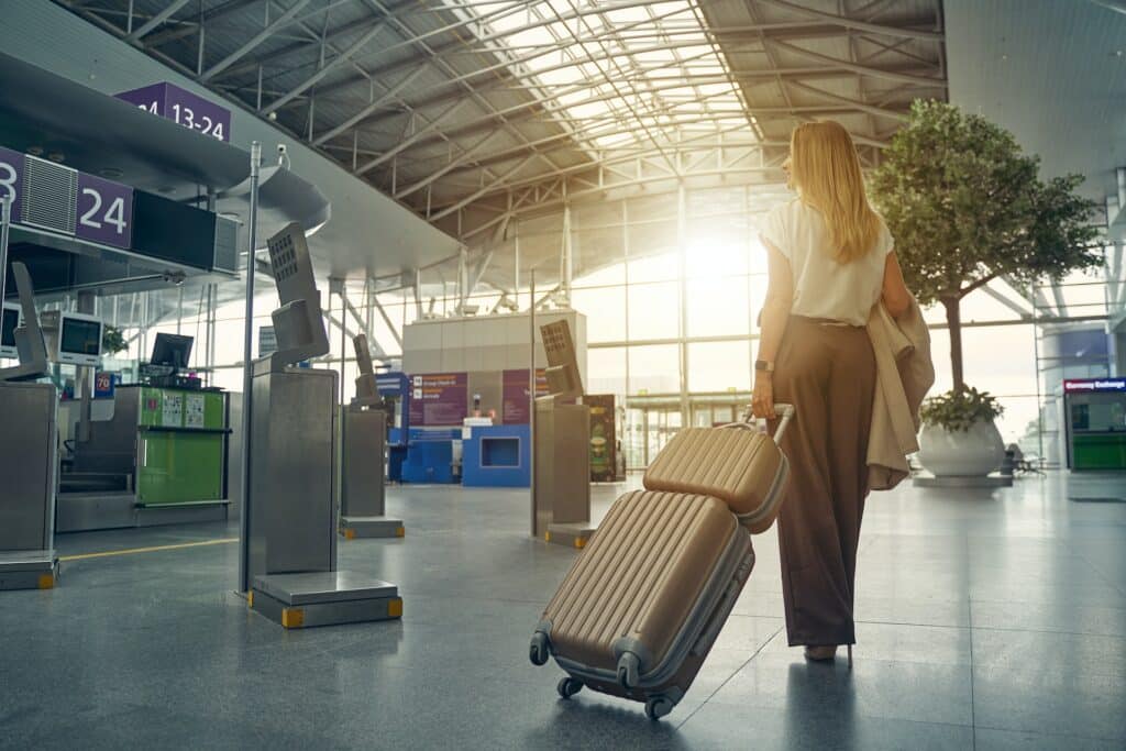 Foreign student awaiting to travel to Singapore under the Work Holiday Pass with luggage in hand at an airport