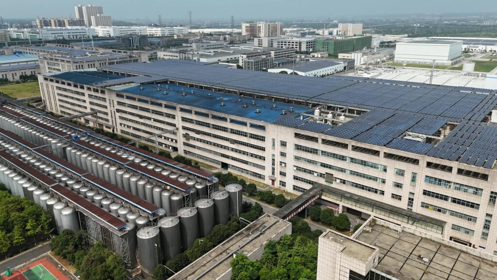 Aerial view of a modern industrial building with solar panels and storage tanks.