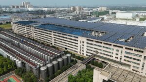 Aerial view of a modern industrial building with solar panels and storage tanks.