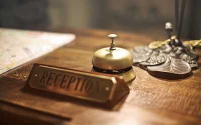 Old fashioned golden service bell and reception sign placed on wooden counter of hotel with retro interior